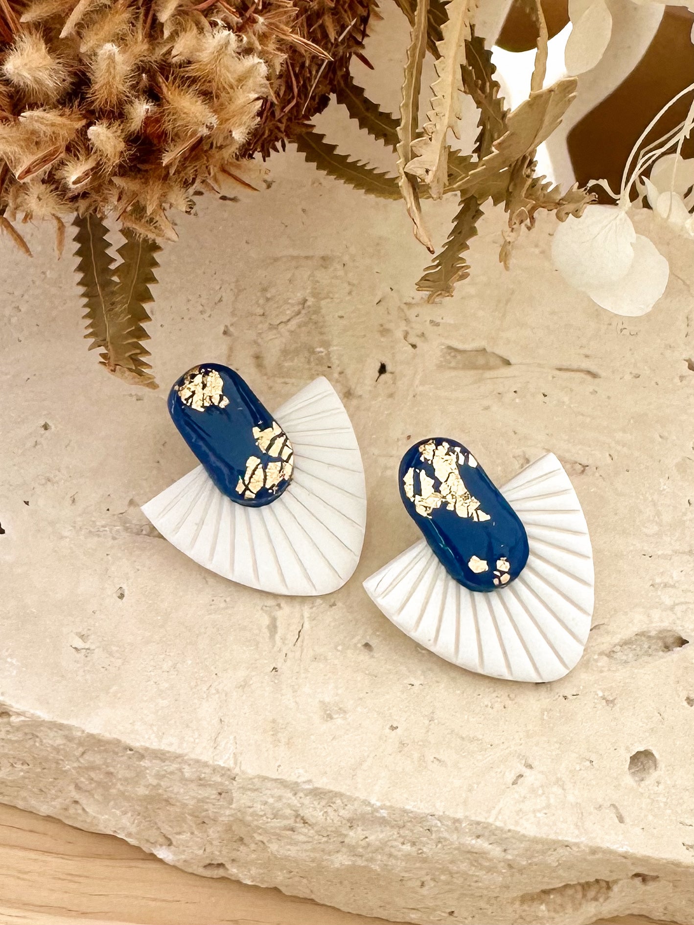 Pair of blue and white earrings on a textured surface with decorative elements.